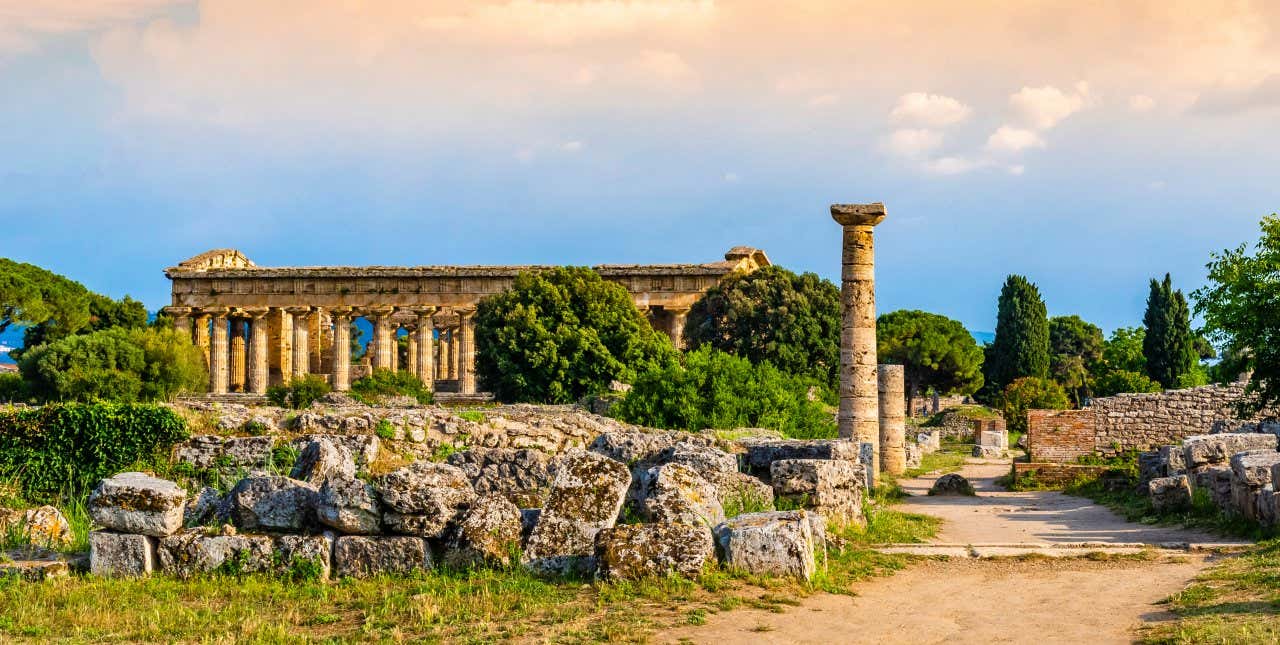 Resti di un tempio greco a >Paestum in un giorno di sole, con alcune colonne in primo piano