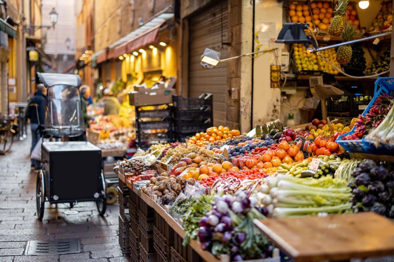 Via gastronomica del Quadrilatero con bancarelle piene di frutta e verdura fresca locale a Bologna
