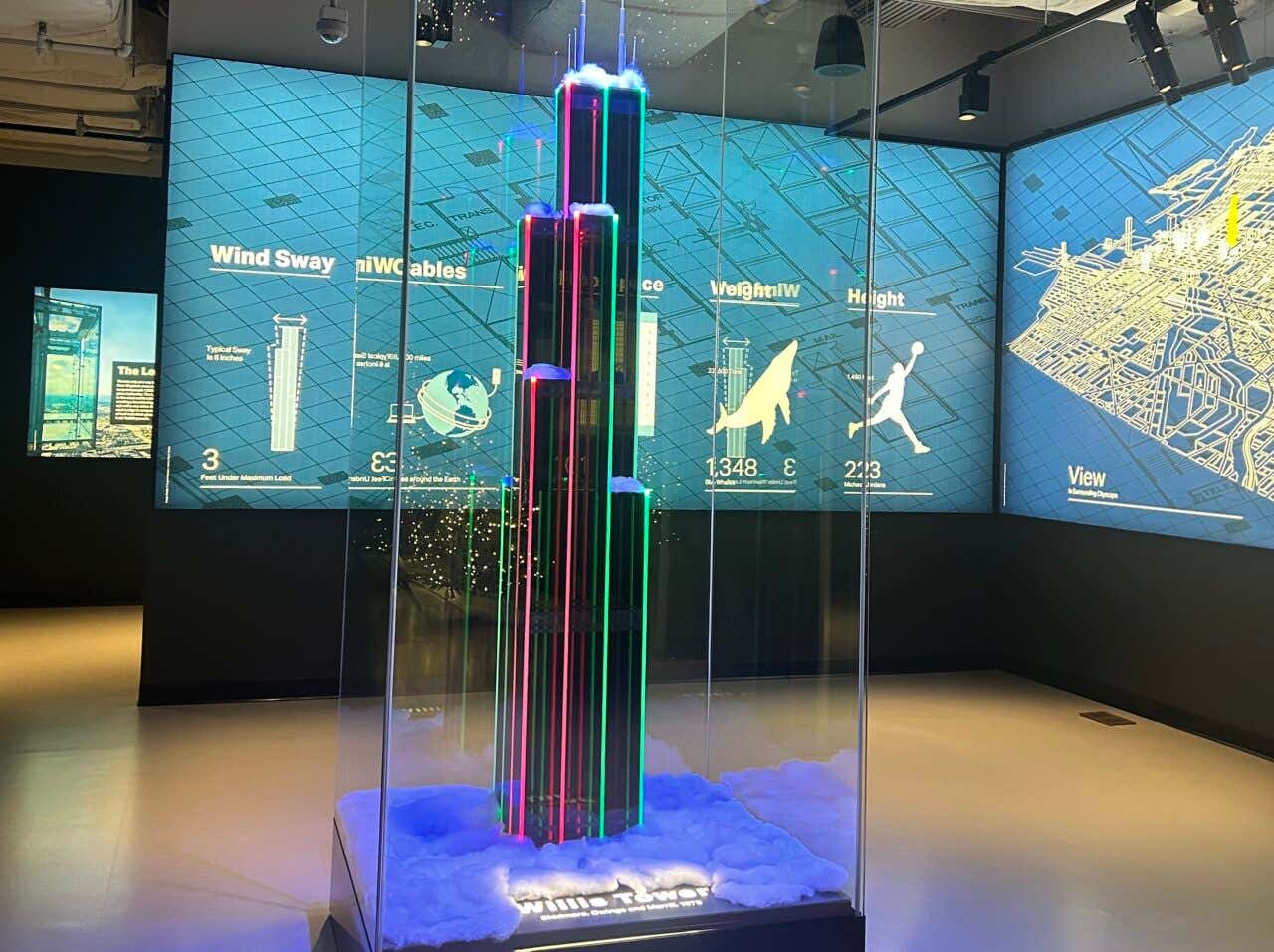 Réplica da Willis Tower na exposição anterior ao Skydeck em frente de um painel com comparativos e um mapa de Chicago