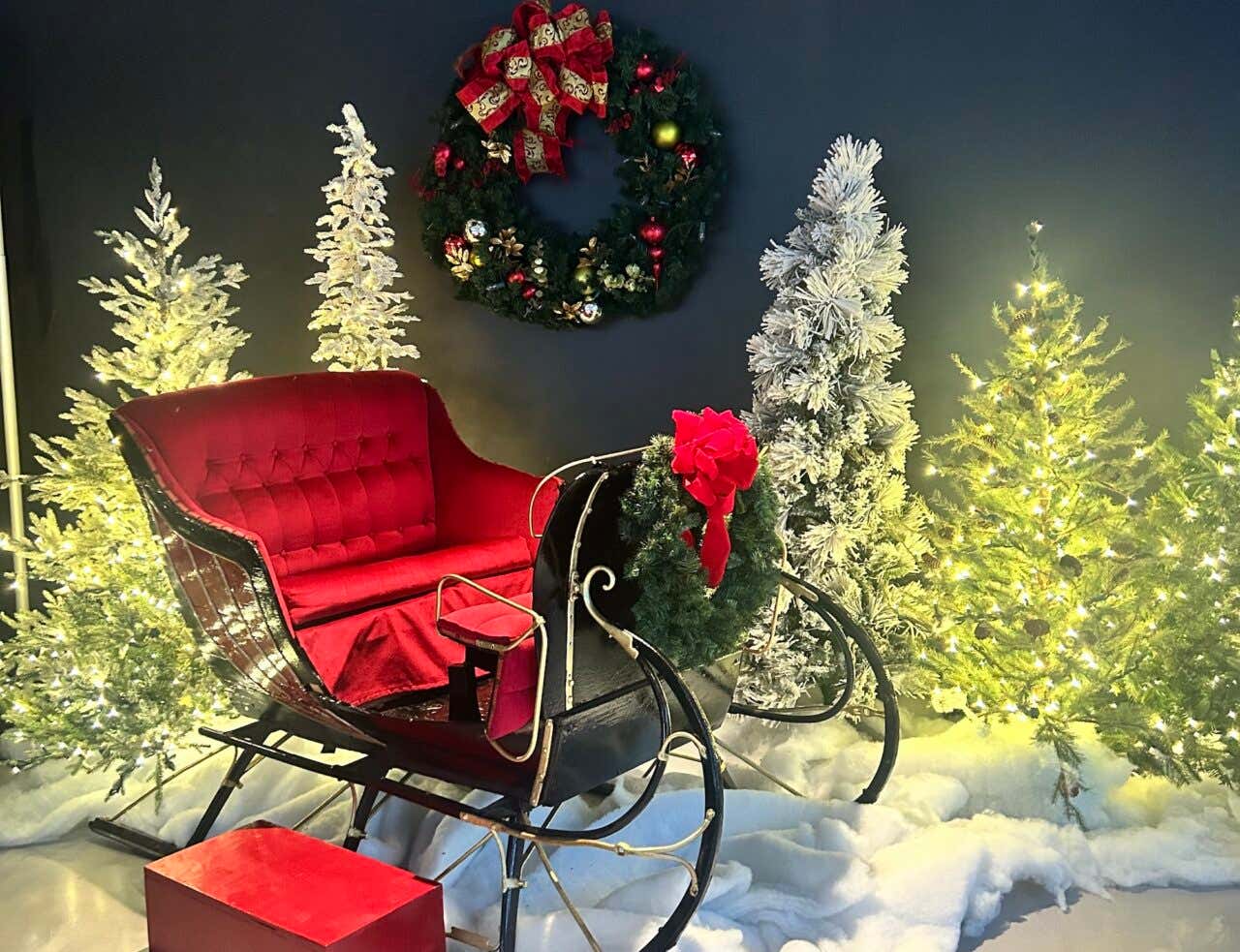 Detalhe de uma decoração natalina, com árvores de Natal e uma guirlanda na parede 
