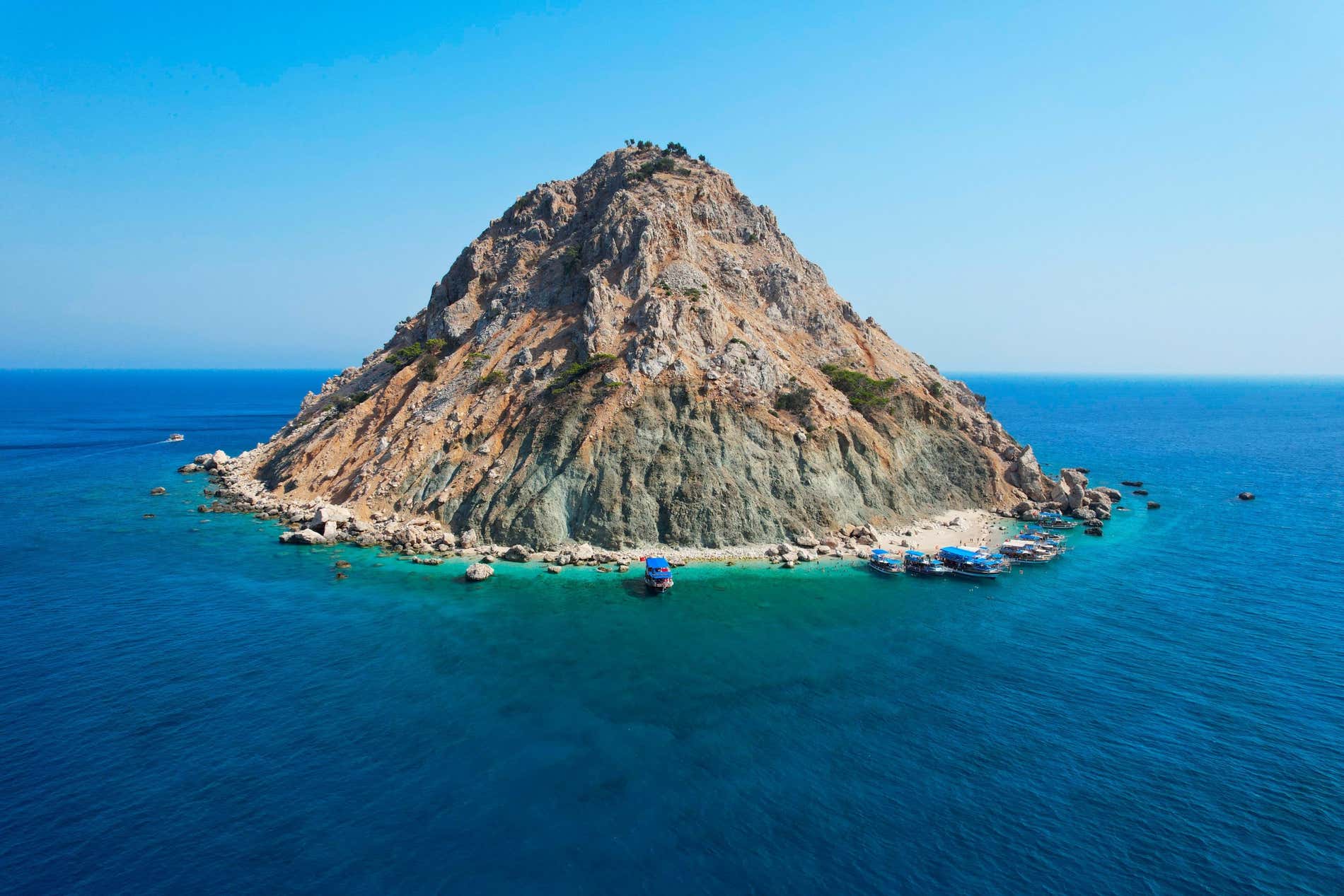 L'isola di Suluada vista dal largo, con le barche ormeggiate sulla riva.