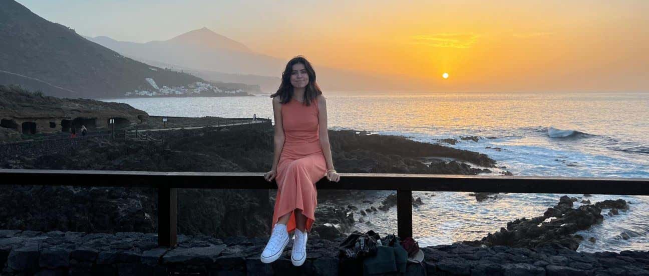Lucía Fernández sentada en el malecón de la playa en el atardecer