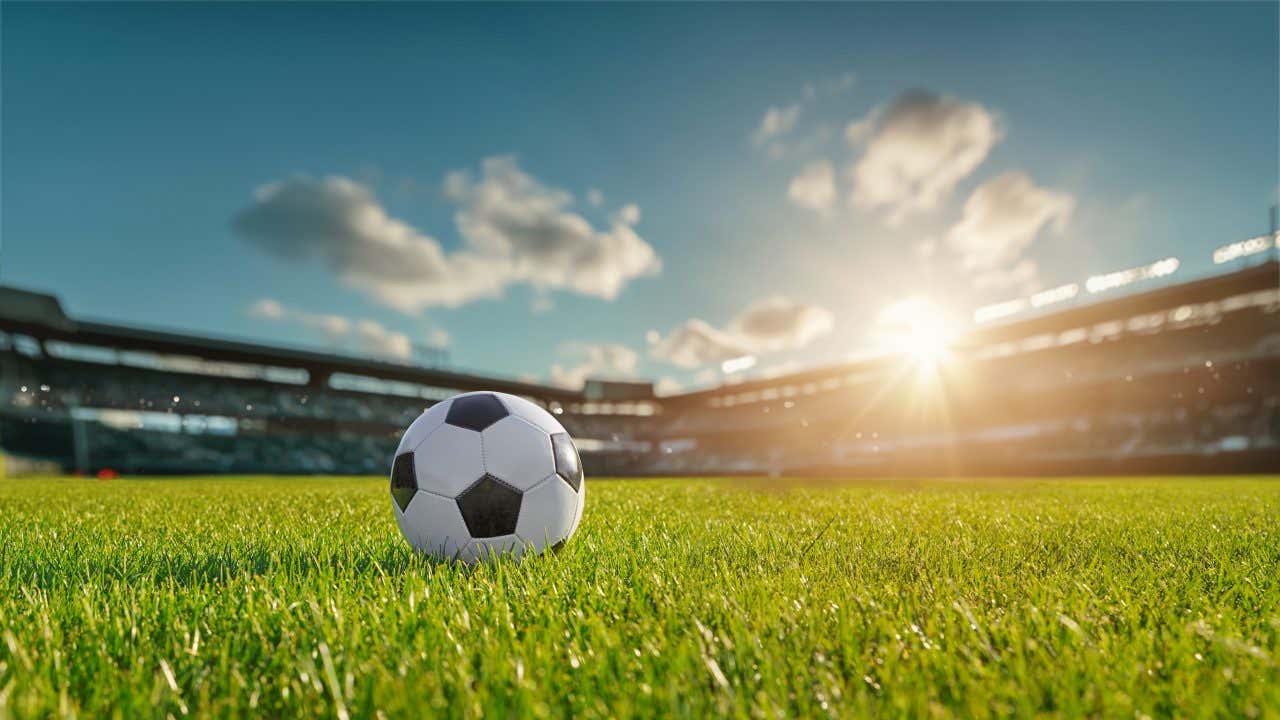 Uma bola de futebol no centro do gramado em um estádio