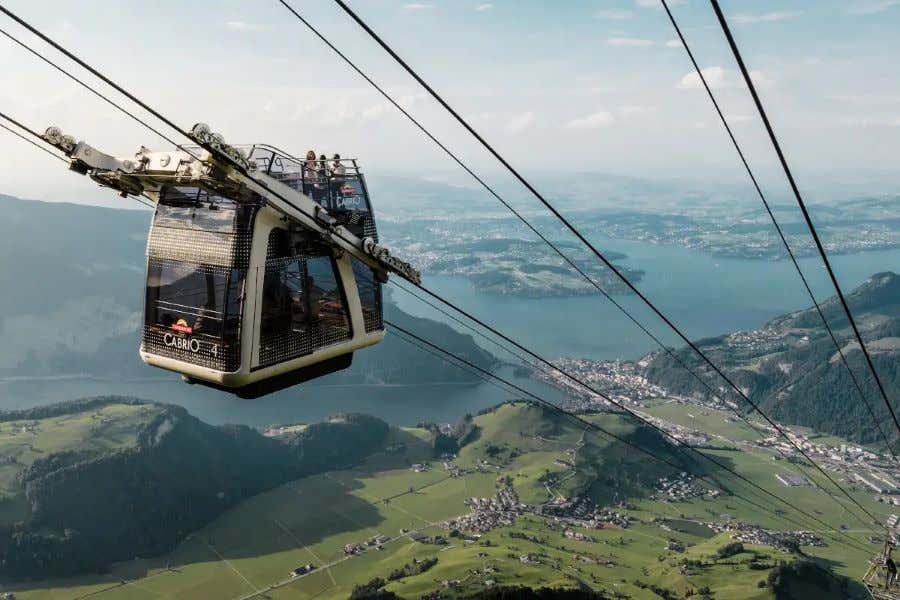 Varias personas observan un lago desde un teleférico panorámico