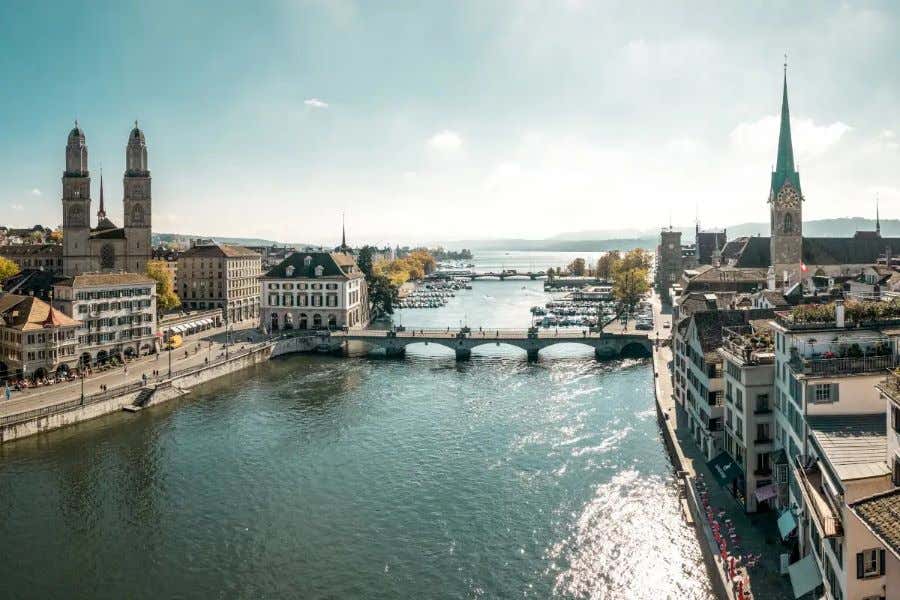 Vista de un río a su paso por una ciudad, con unos campanarios de fondo