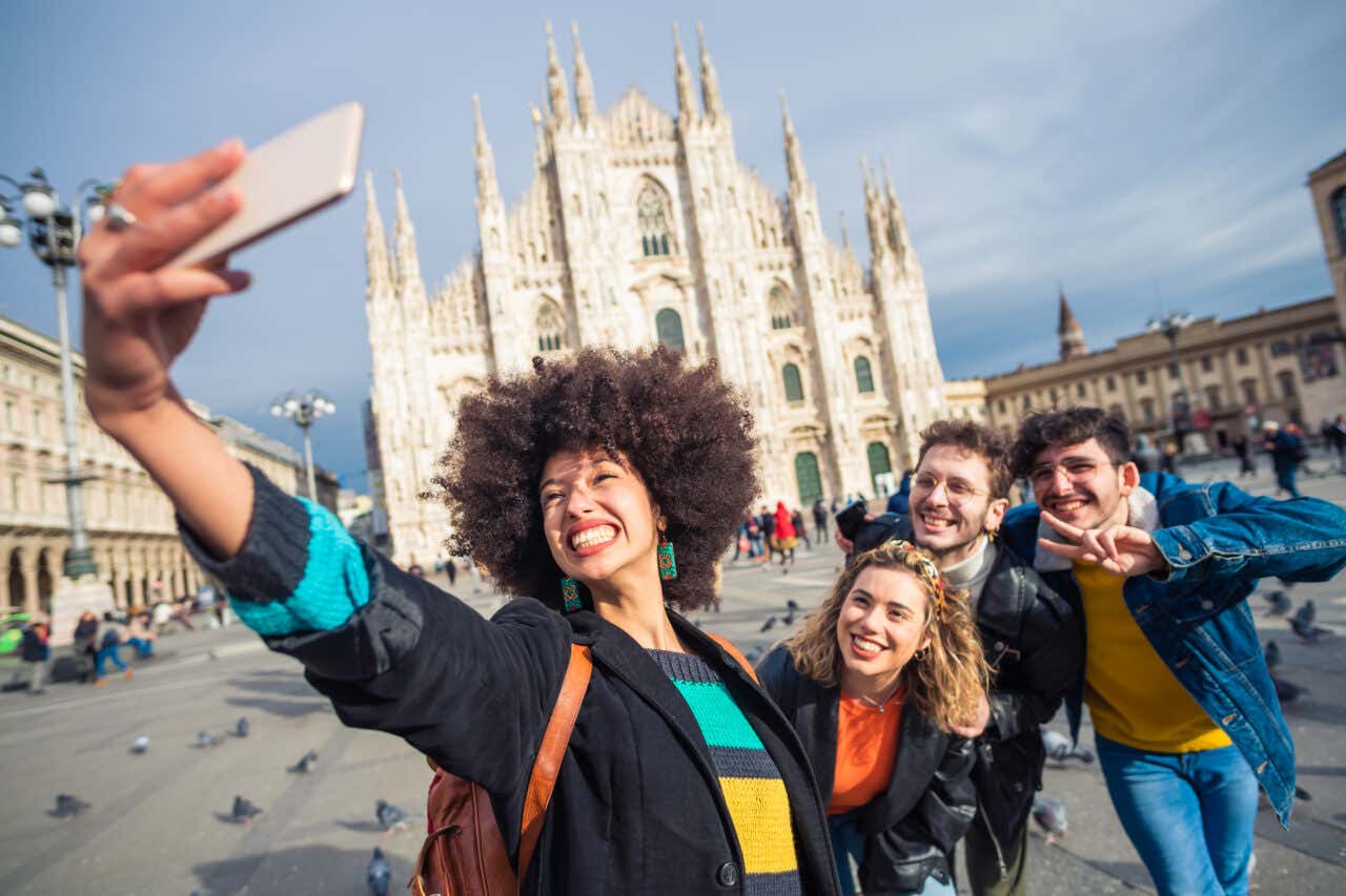 Un gruppo di quattro amici in piazza del Duomo a Milano mentre si scattano un selfie