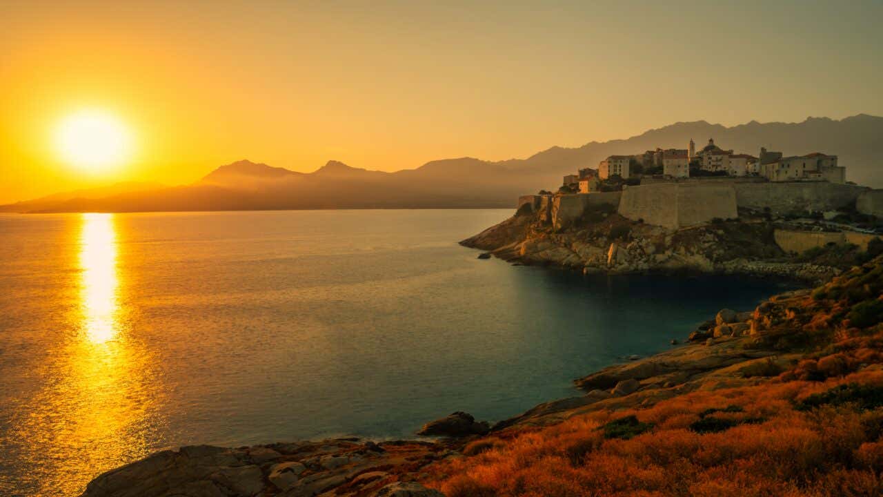 Una città fortificata affacciata sul Mediterraneo al tramonto