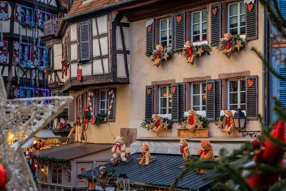 Tradizionali case a graticcio decorate con ornamenti rossi e dorati e orsacchiotti al famoso mercatino di Natale di Colmar, in Francia