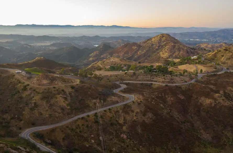 Vista aérea da Mullohand Drive, uma estrada sinuosa rodeada de montanhas