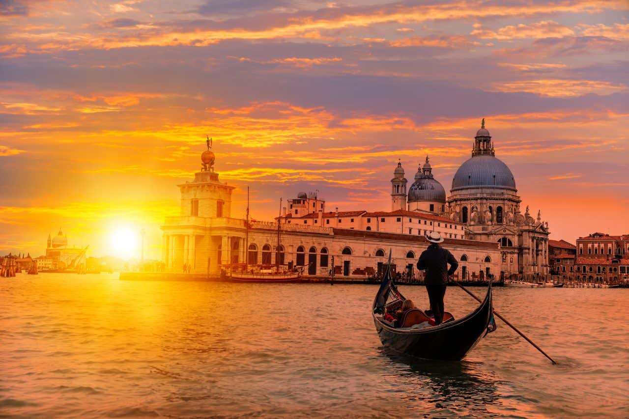 A gondola sailing in Venice at sunset.