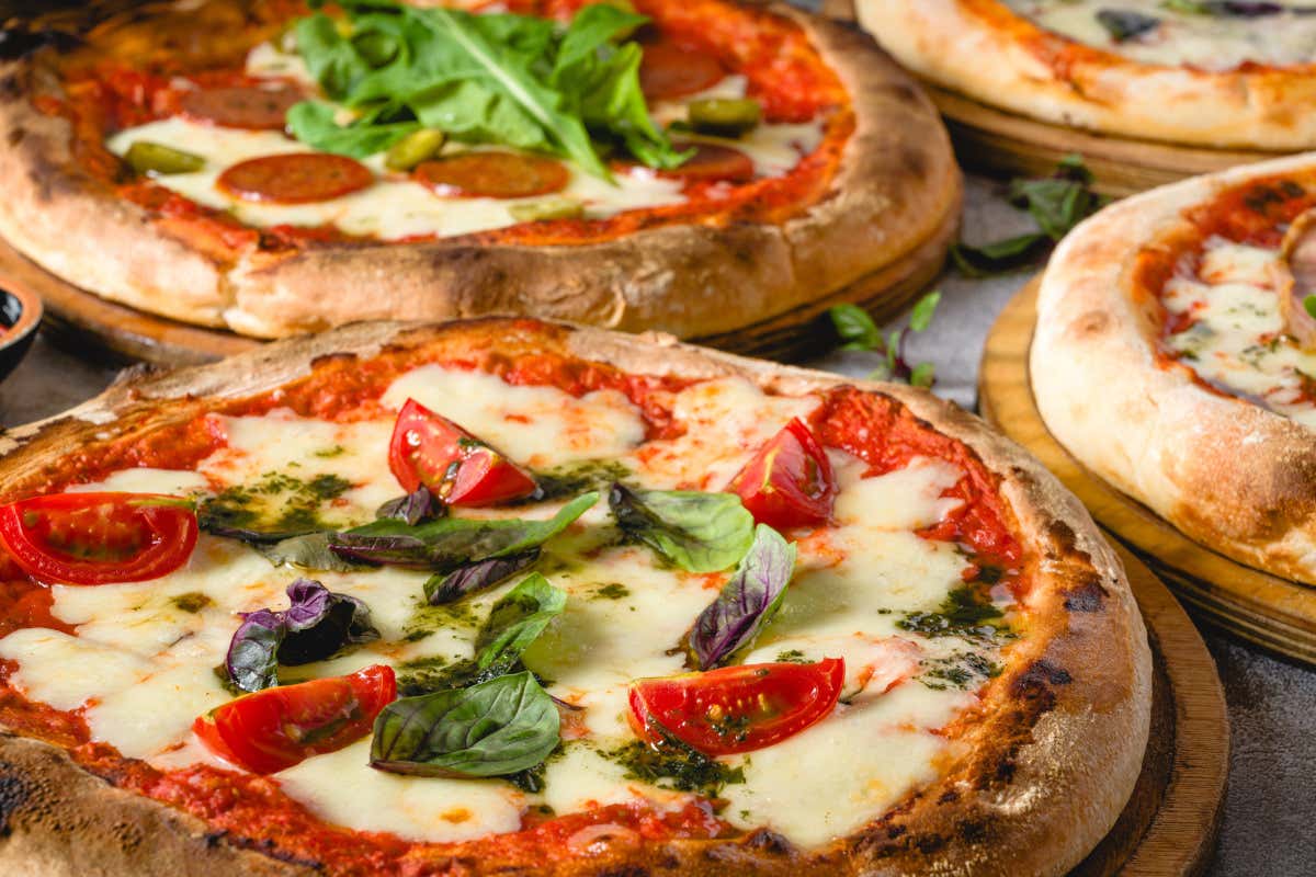 Detalle de varias pizzas napolitanas con tomate, queso y albahaca sobre una mesa