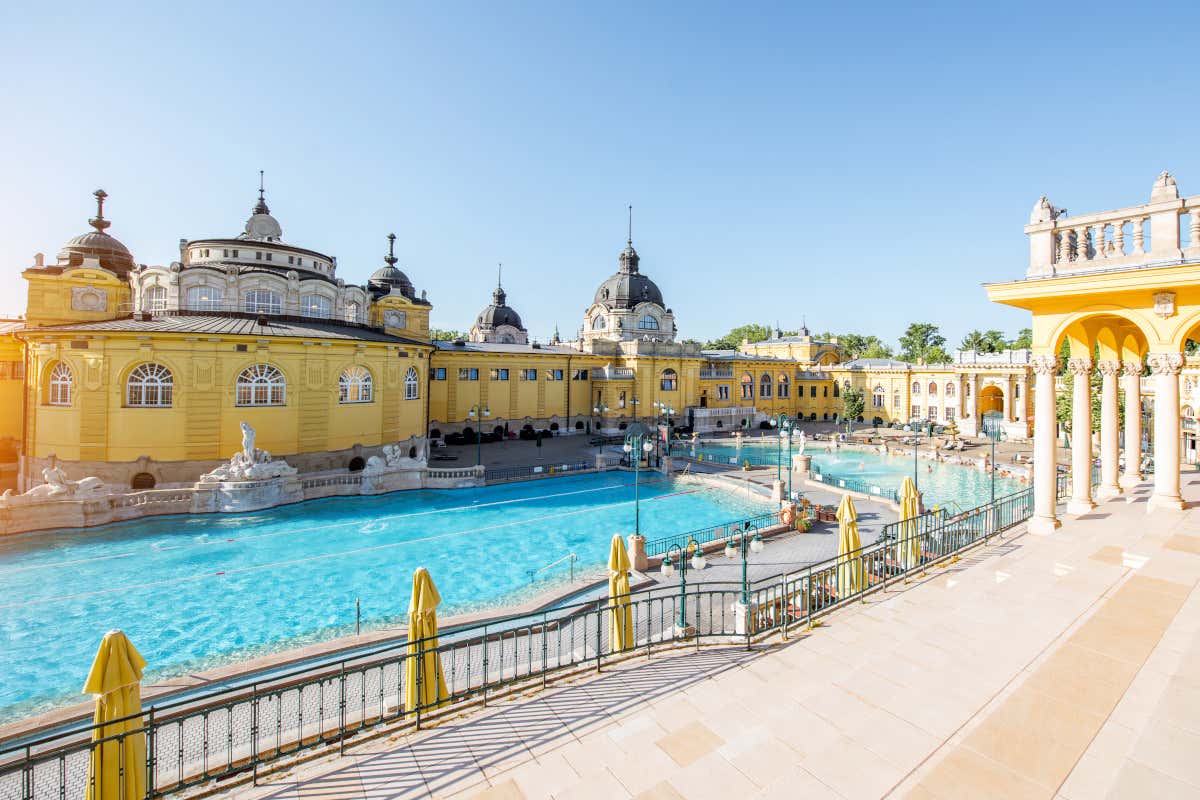Detalle de una piscina al aire libre del balneario de Széchenyi de Budapest, con un gran complejo de edficios de color amarillo de fondo