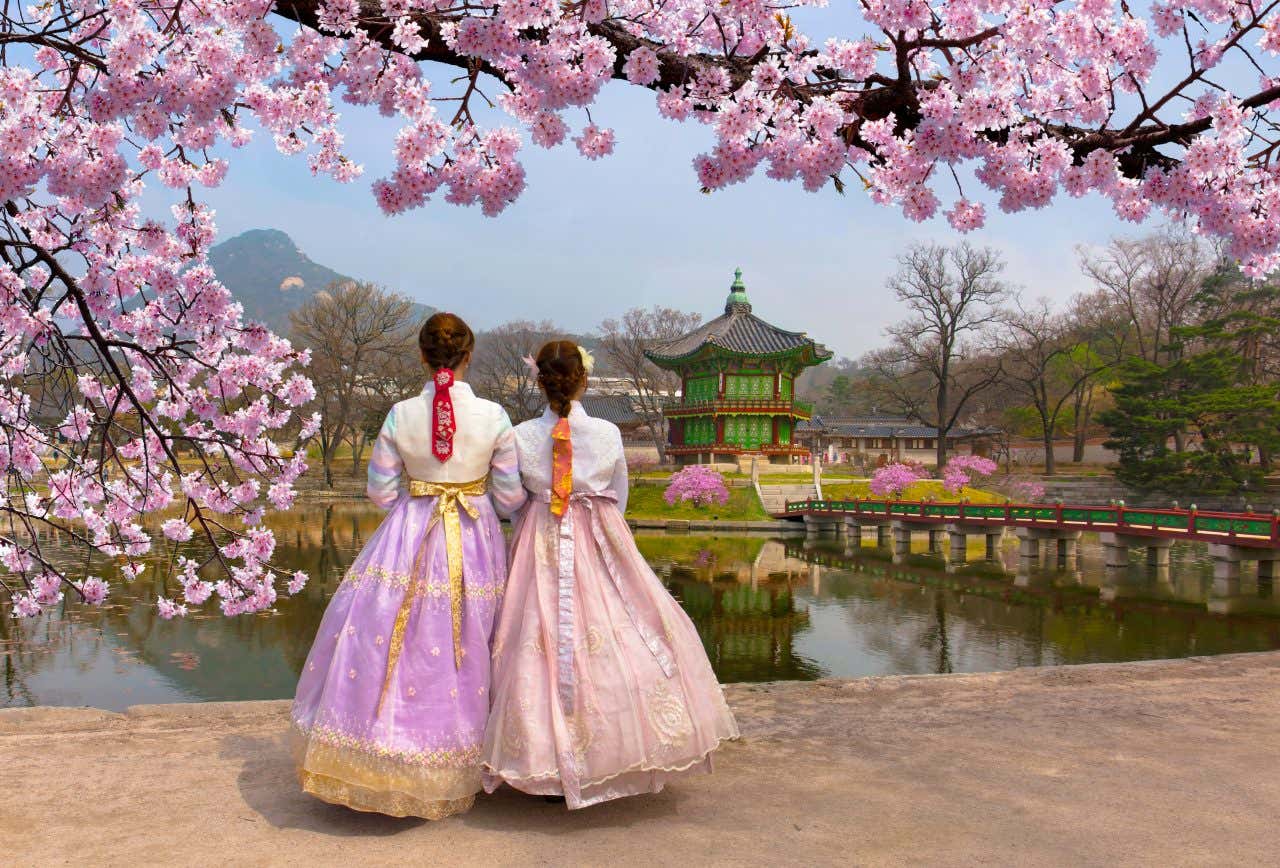 Deux jeunes femmes de dos devant le Palais Gyeongbokgung de Séoul, une ville à visiter au printemps