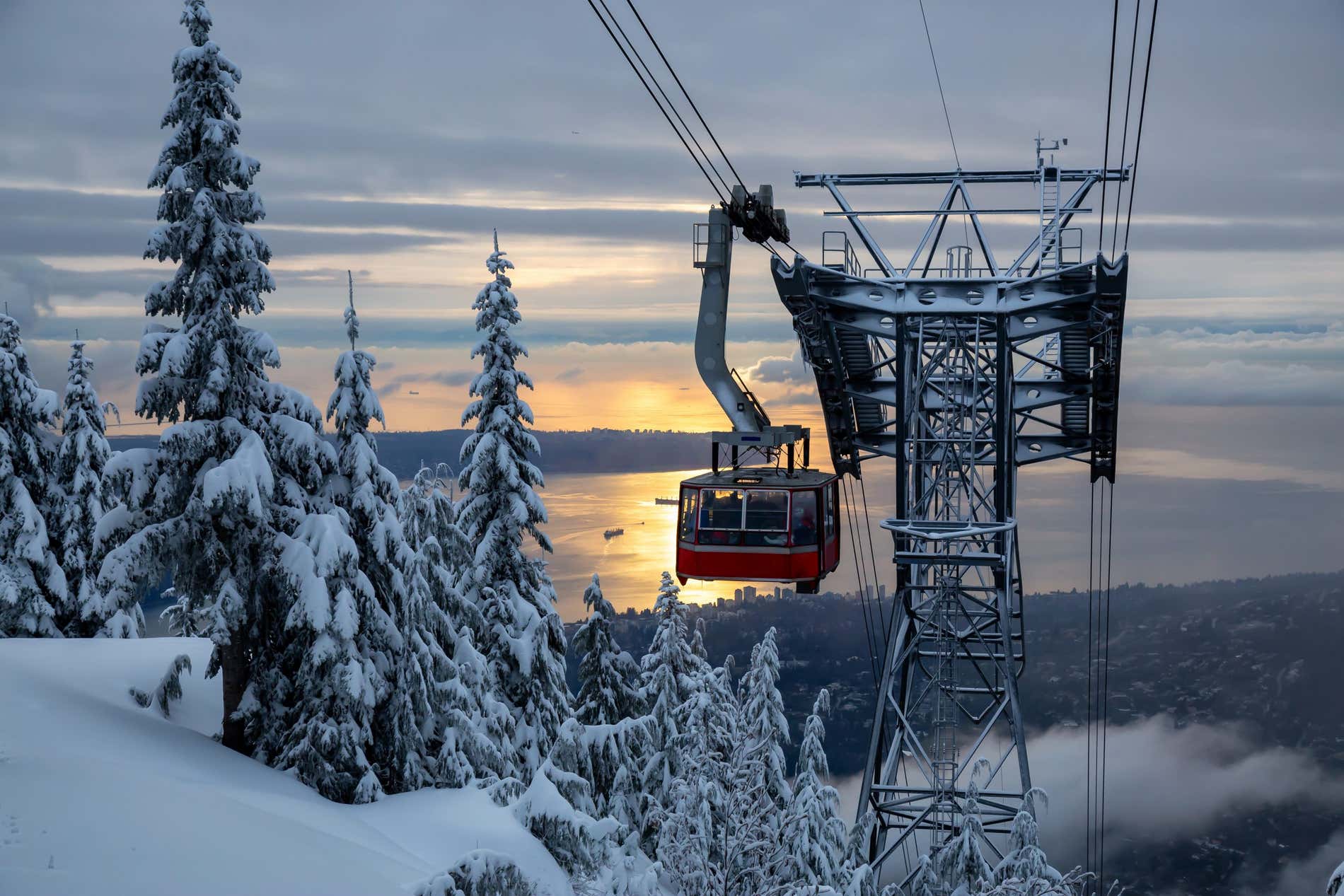 Grouse Mountain con una funivia circondata da alberi innevati e il mare sullo sfondo