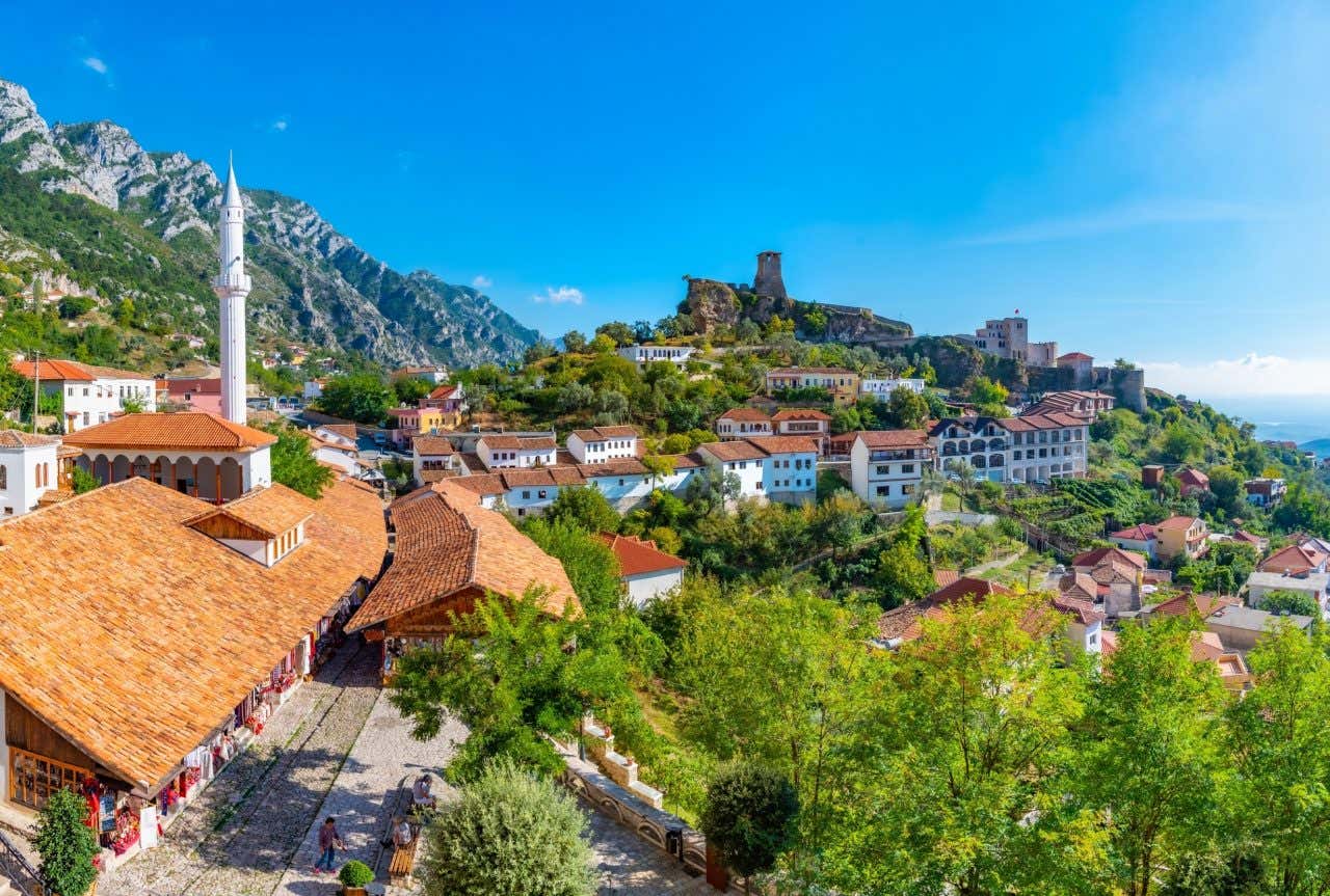 Vista di un piccolo paesino immerso nel verde in cima a un monte e sormontato dai resti di un antico castello in rovina in un giorno di sole