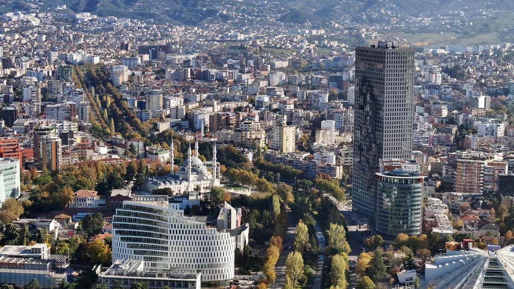 Il centro di Tirana fotografato dall'alto in una giornata soleggiata, con i grattacieli moderni a poca distanza da un'antica moschea