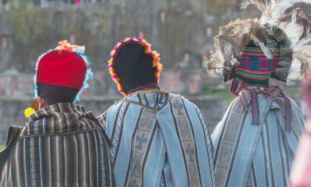 Tre persone in abiti cerimoniali inca fotografati di spalle a Cusco durante una festa tradizionale