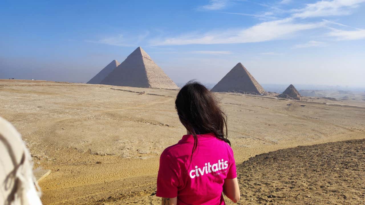 Una mujer de espaldas con un polo de Civitatis frente a las pirámides de Giza