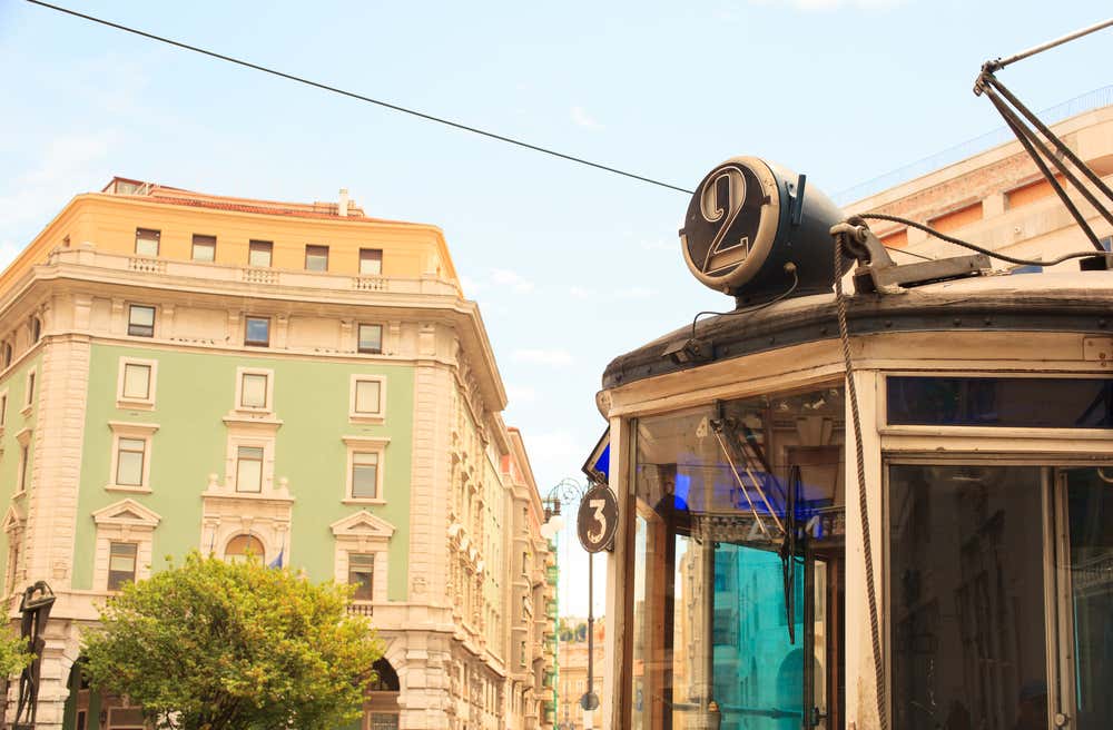 Dettaglio della parte anteriore di un antico tram che porta il numero due, sullo sfondo i palazzi del centro di Trieste