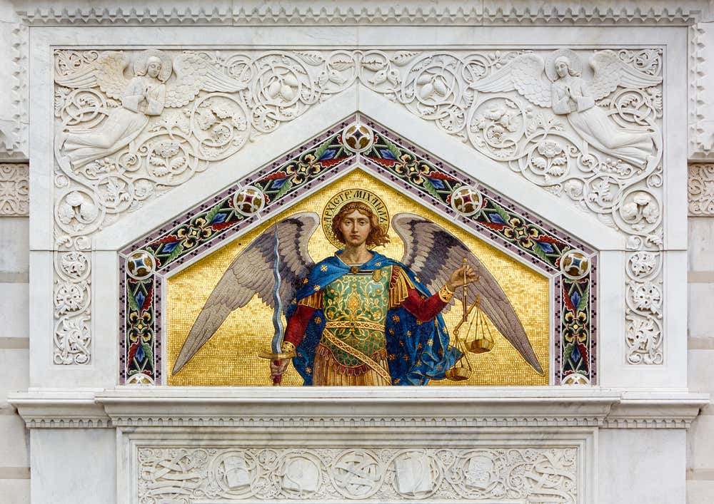 Una cornice in marmo riccamente decorata con motivi naturali che circondano un mosaico policromo a sfondo dorato che rappresenta un angelo con spada e bilancia