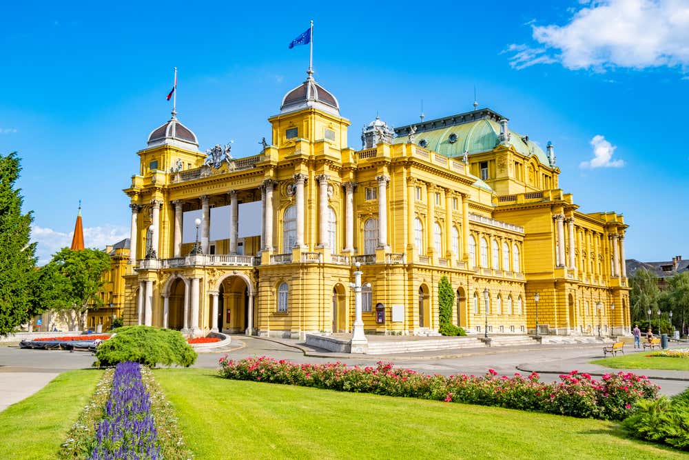 Facciata del Teatro Nazionale Croato di Zagabria, un'elegante costruzione in stile neobarocco con colonne imponenti e di un colore giallo acceso distintivo