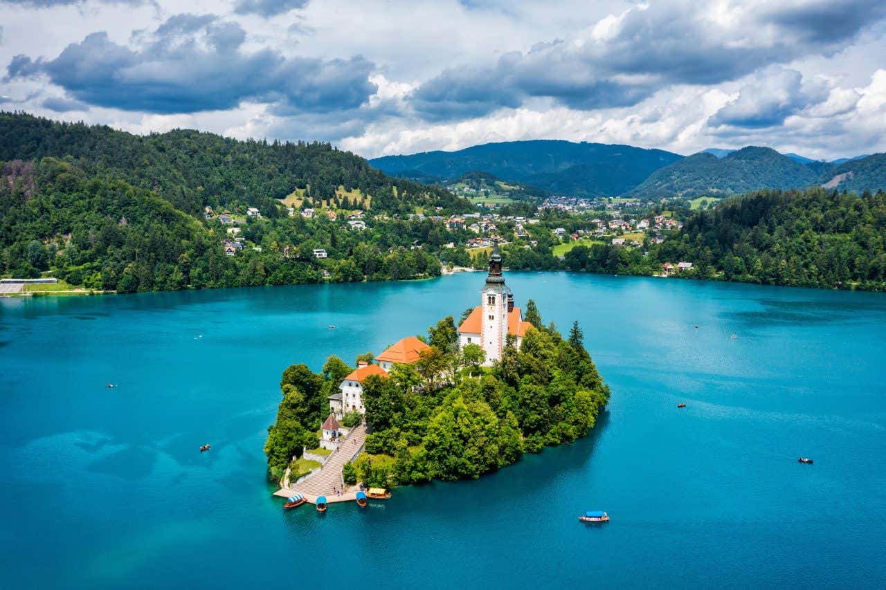 Un'isolotto al centro di un lago circondato da colline e boschi rigogliosi in un giorno nuvoloso