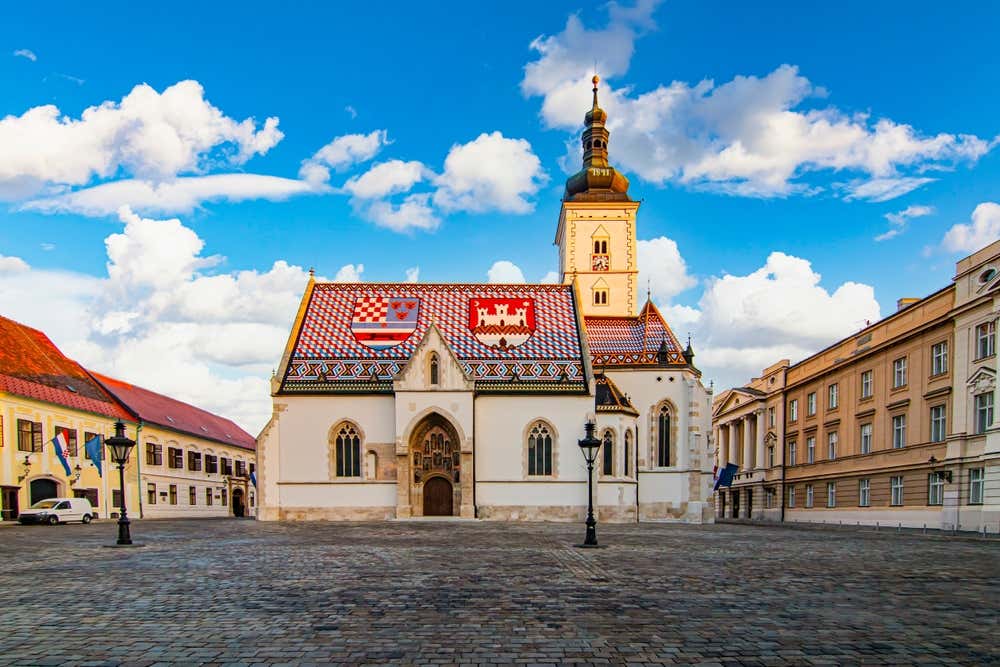 Veduta della Chiesa di San Marco a Zagabria, con il suo caratteristico tetto colorato, raffigurante lo stemma della Croazia, della Dalmazia e della Slavonia. La facciata gotica e l'ingresso principale arricchiscono l'eleganza architettonica della piazza circostante