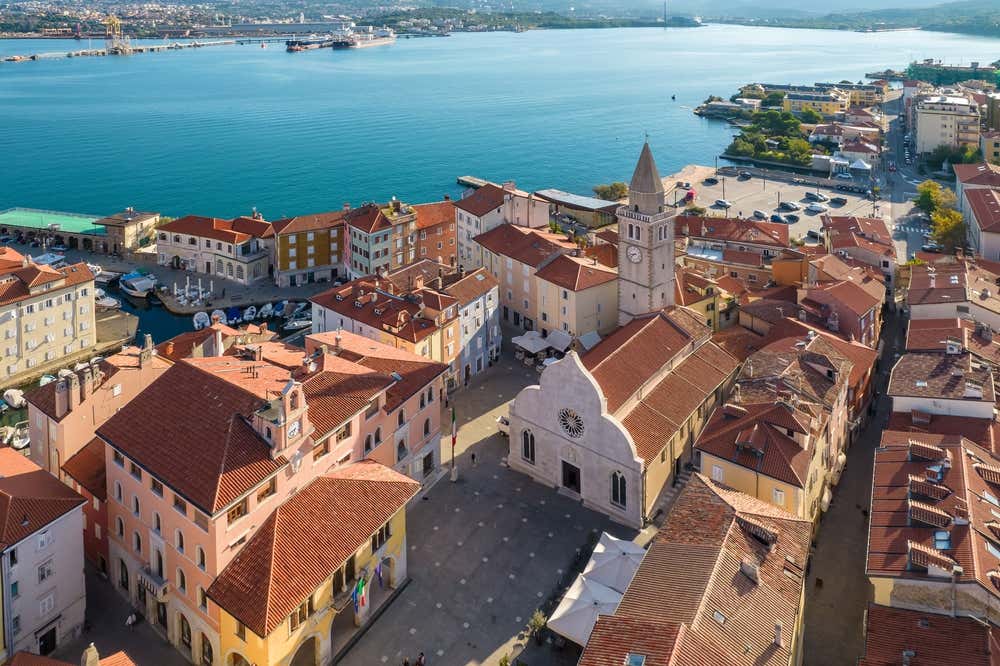 Veduta aerea del centro storico di Muggia, con la piazza principale, la cattedrale e il castello di Muggia. Sullo sfondo il Golfo di Trieste