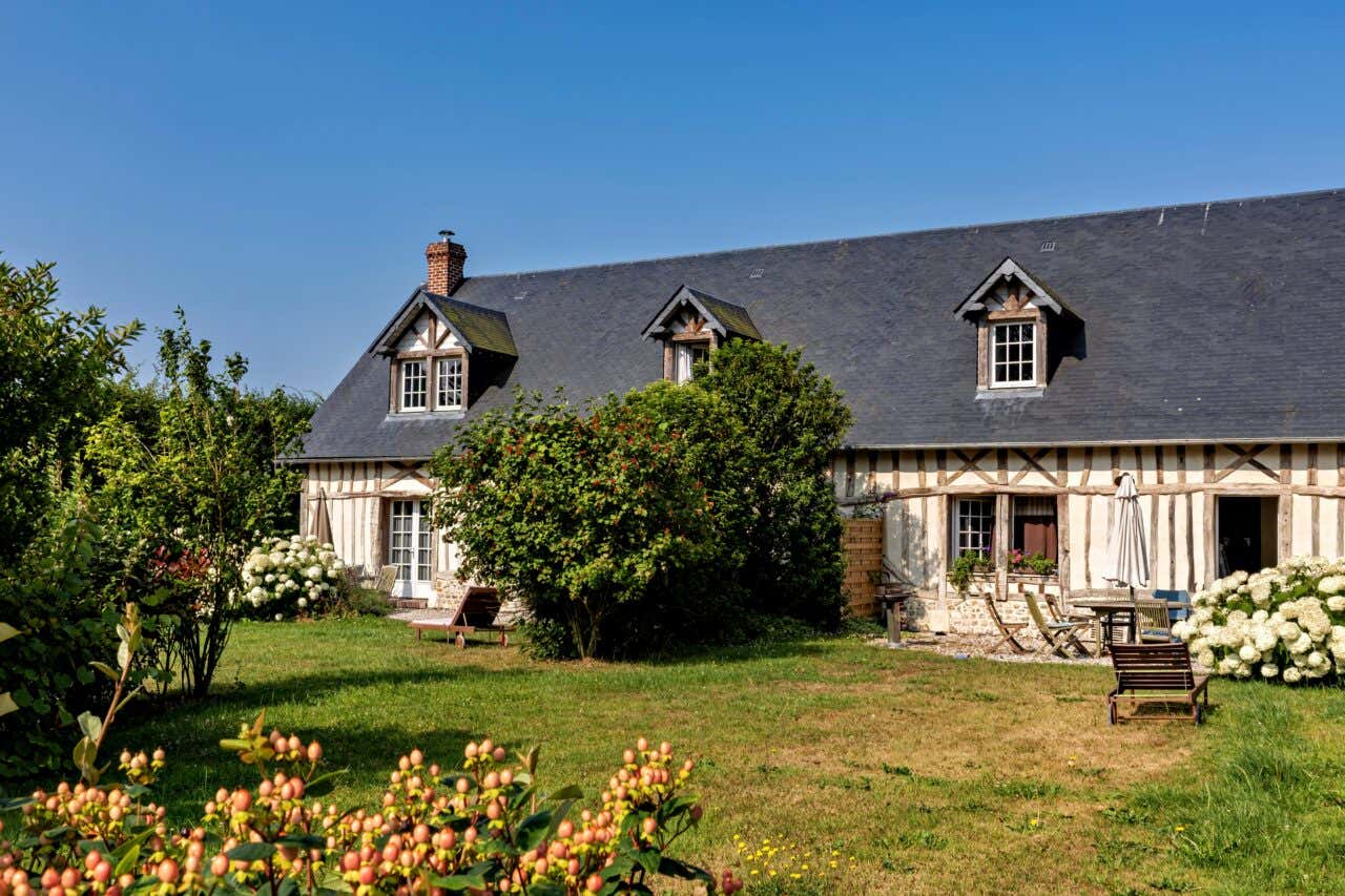 Una casa antica in Normandia, con tetto a spiovente immersa in incantevole giardino in una giornata di sole