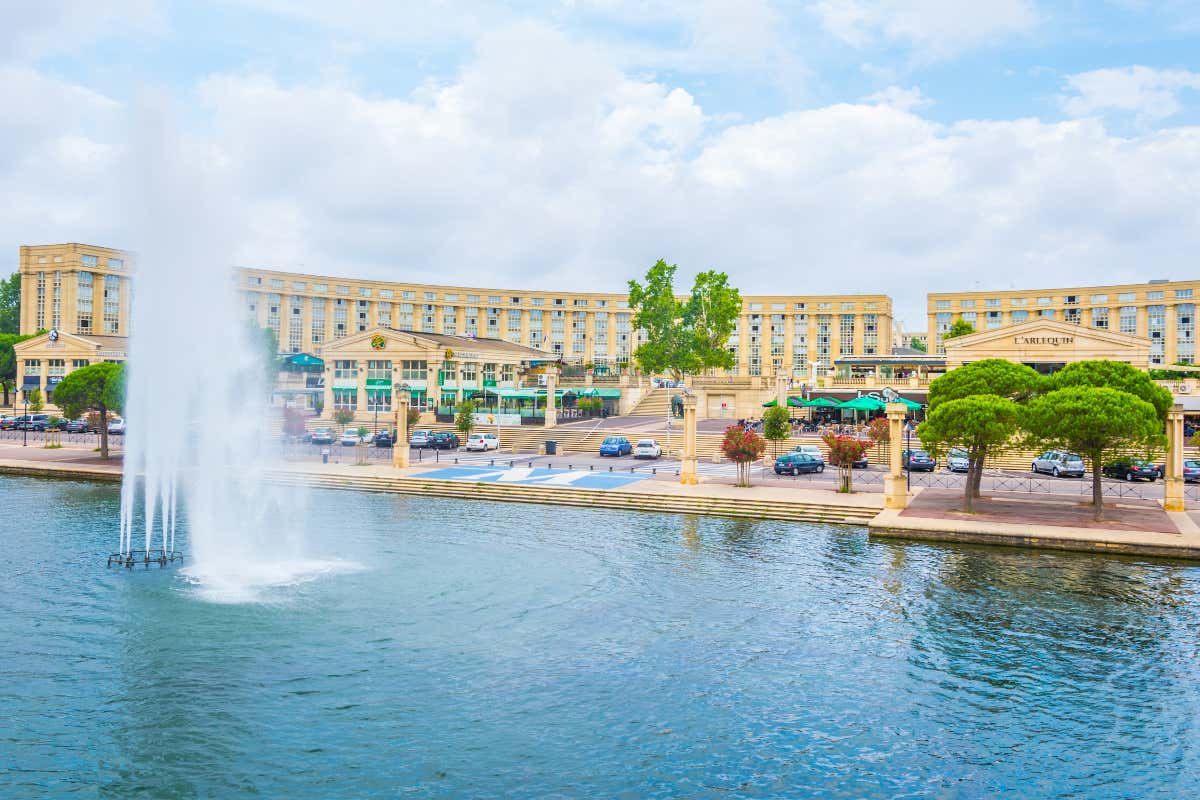 Fuente ornamental sobre el río Lez frente a unos edificios de color amarillo en Montpellier