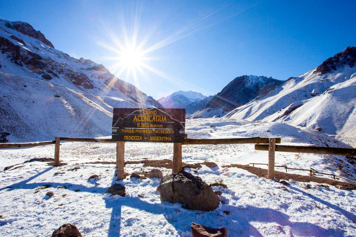 La entrada al Parque Provincial del Aconcagua donde se aprecia una letrero en madera y montañas nevadas