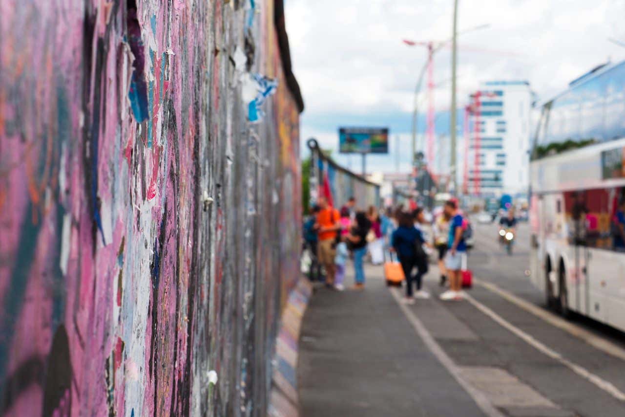 Touristes regardant les décors sur le Mur de Berlin à East Side Gallery, une visite à faire à Berlin