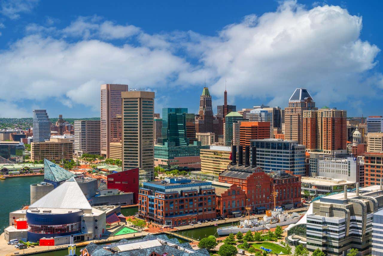 Aerial panoramic view of Baltimore and the Inner Harbor on a sunny day. The National Aquarium visible and the USS Constellation.