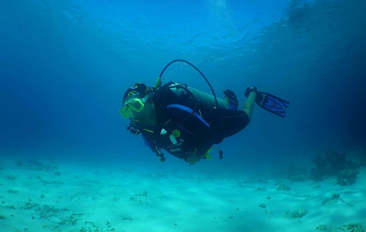Uma mulher com equipamento de mergulho nas águas turquesas do Caribe