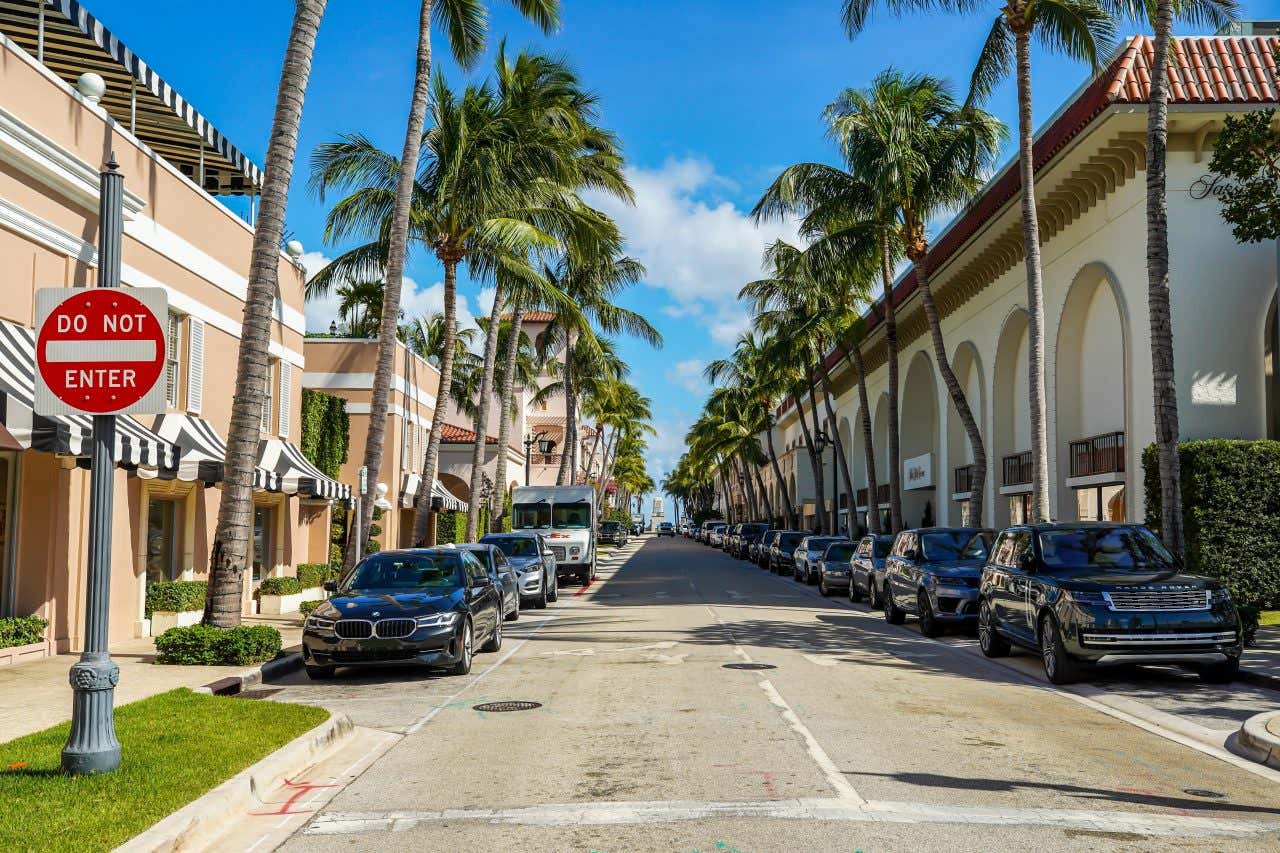 A street in West Palm Beach with cars parked along both sides of the road.