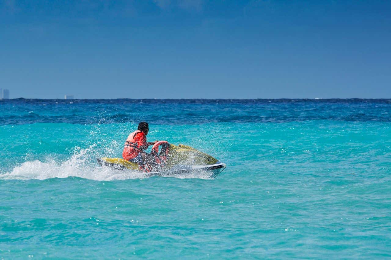 Um homem andando de jet ski no mar turquesa