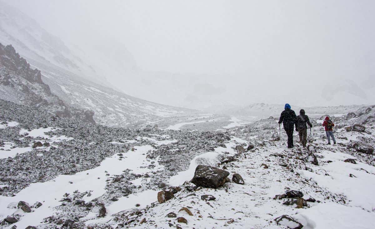 Unas personas realizando una ruta de trekking en una montaña nevada rodeados de neblina