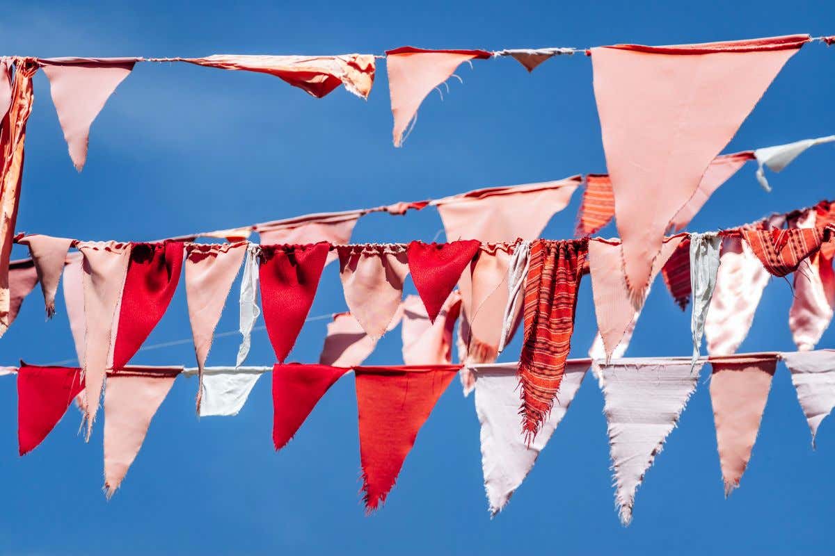 Unas banderillas de colores rosas y rojos cuelgan en el cielo azul