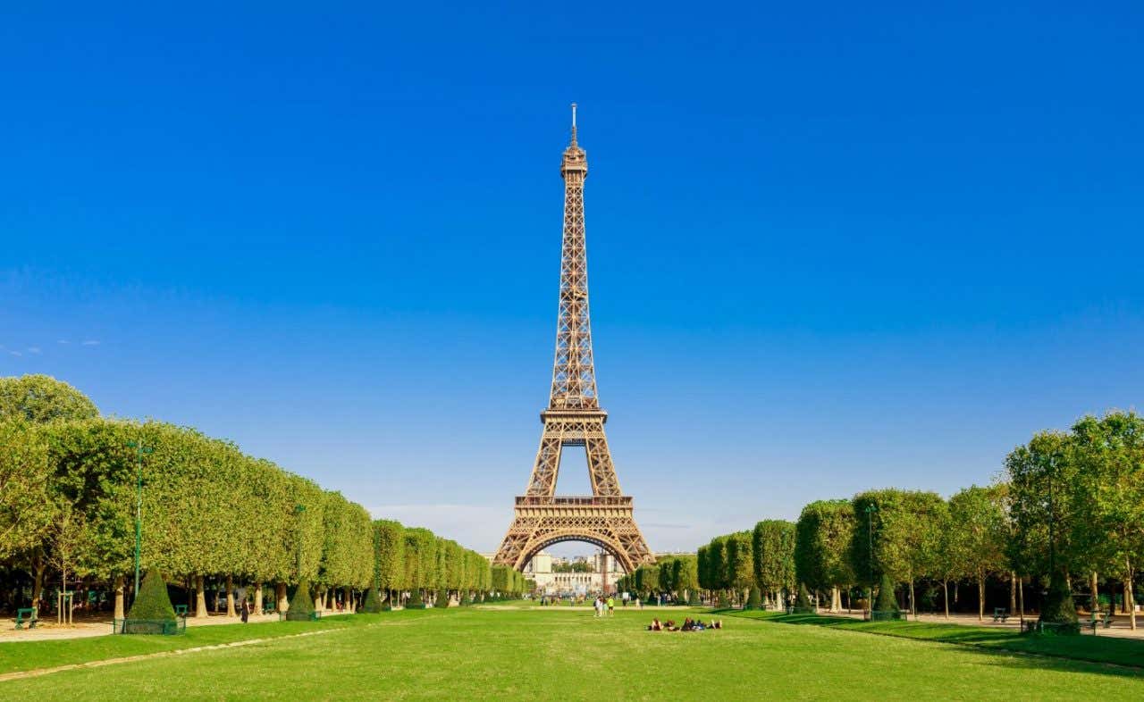La Torre Eiffel vista desde el Campo de Marte donde se aprecia la arboleda en un día soleado