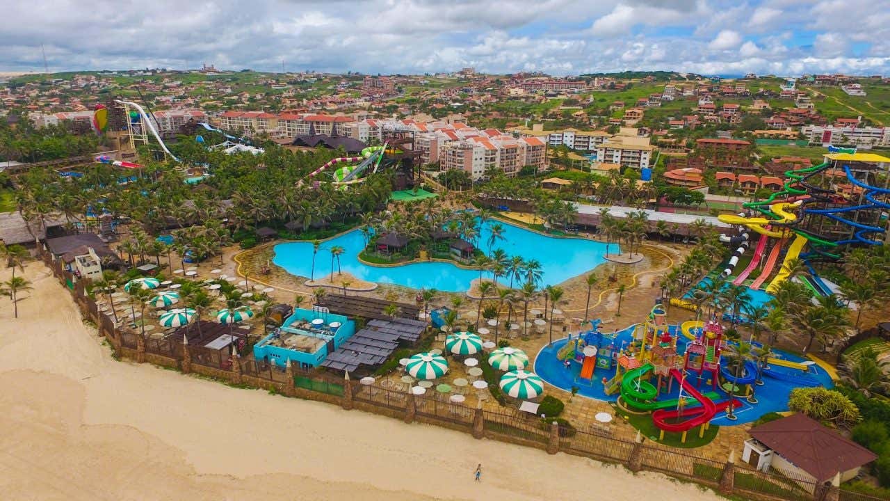 Complexo de parque aquático do Beach Park com diversos guarda-sóis, piscinas, toboáguas e resorts