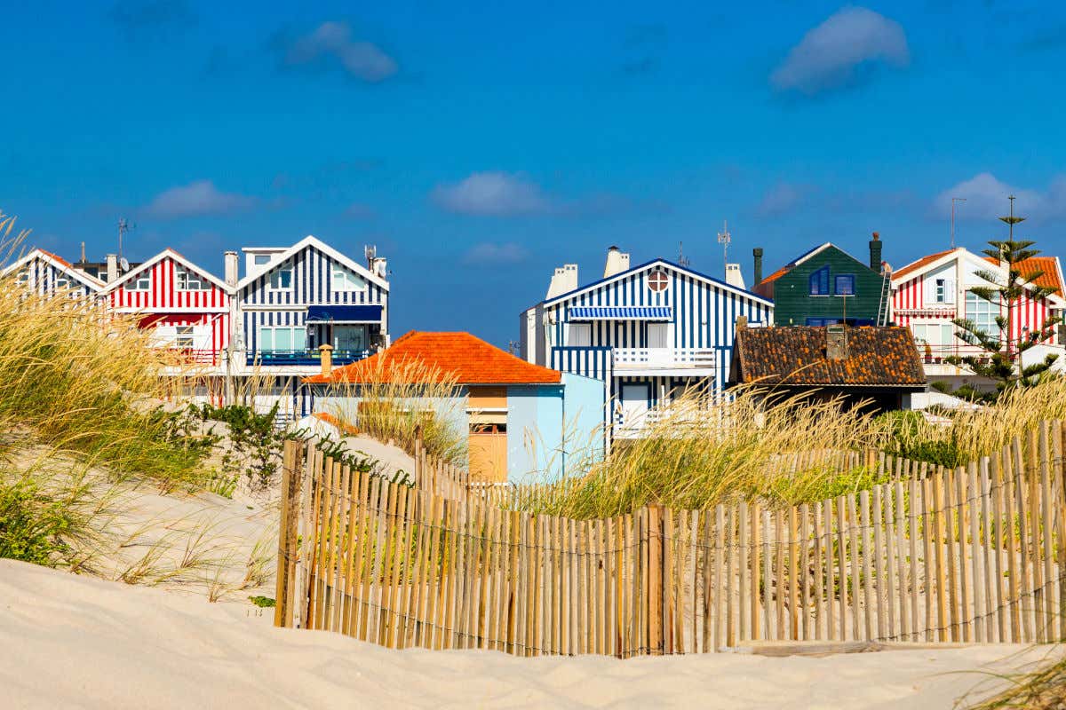 Casas de colores escondidas entre dunas de arena en una playa