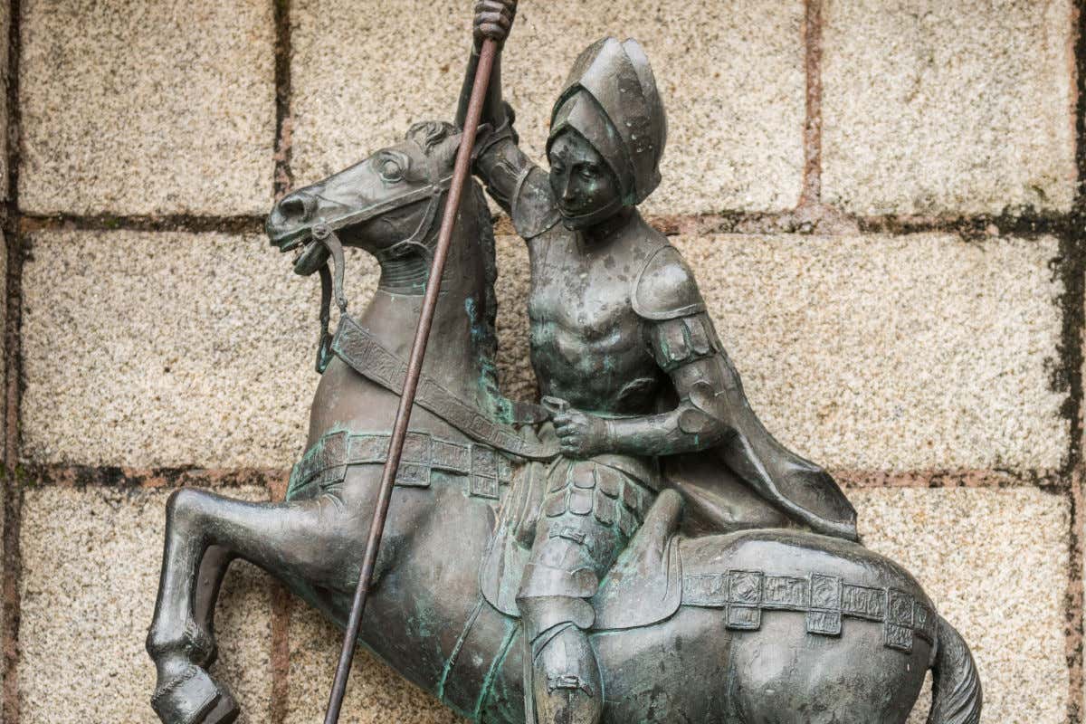 Escultura ecuestre hecha en bronce de San Jorge sobre un caballo y apuntando con una lanza