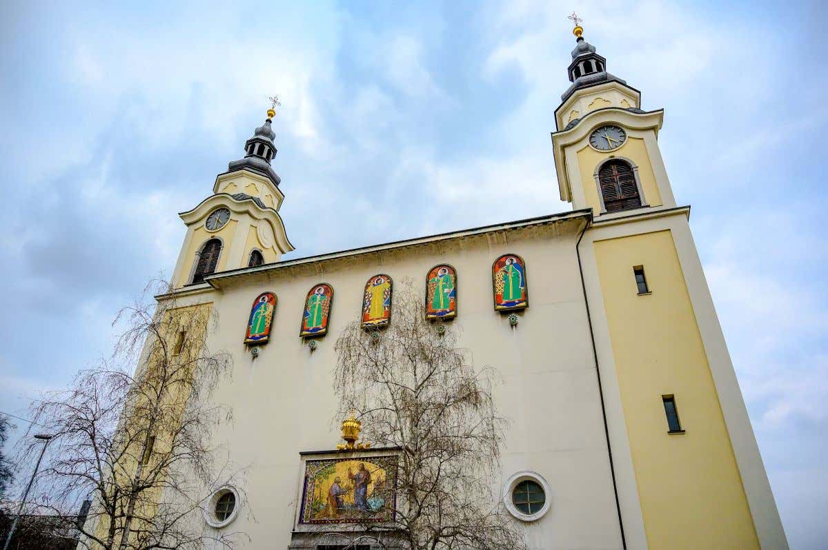 Una iglesia católica de tonos amarillos con ventanales pequeños vista desde abajo