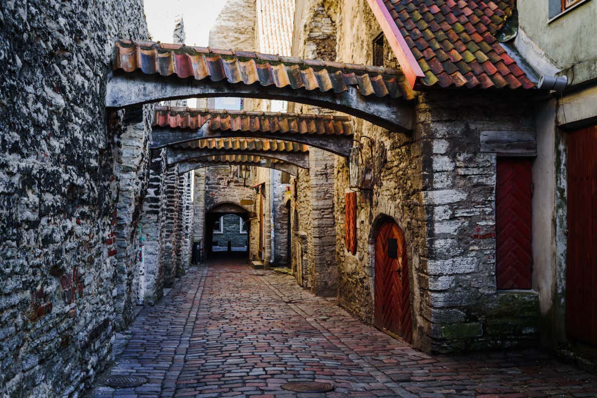 Una calle adoquinada de aspecto antiguo y con varios arcos uniendo sus muros