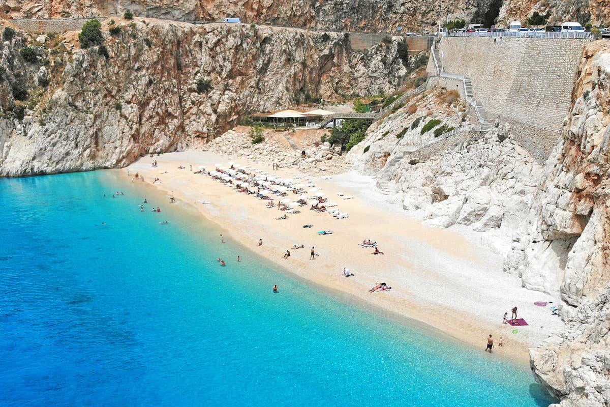 Vista aérea de una playa de aguas turquesas y fina arena dorada, con unas escaleras de piedra al fondo