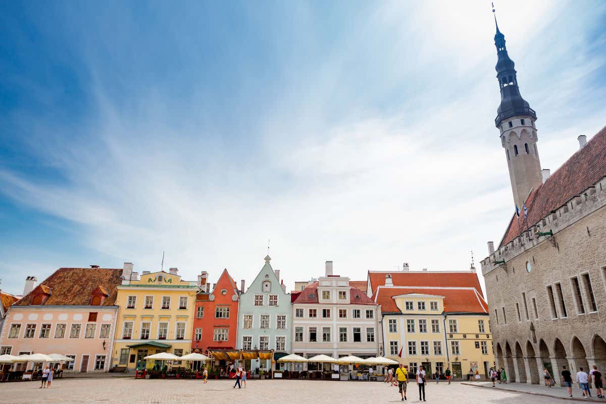 Varias casas de colores rodeando al ayuntamiento de Tallin, que lama la atención por su pequeña torre