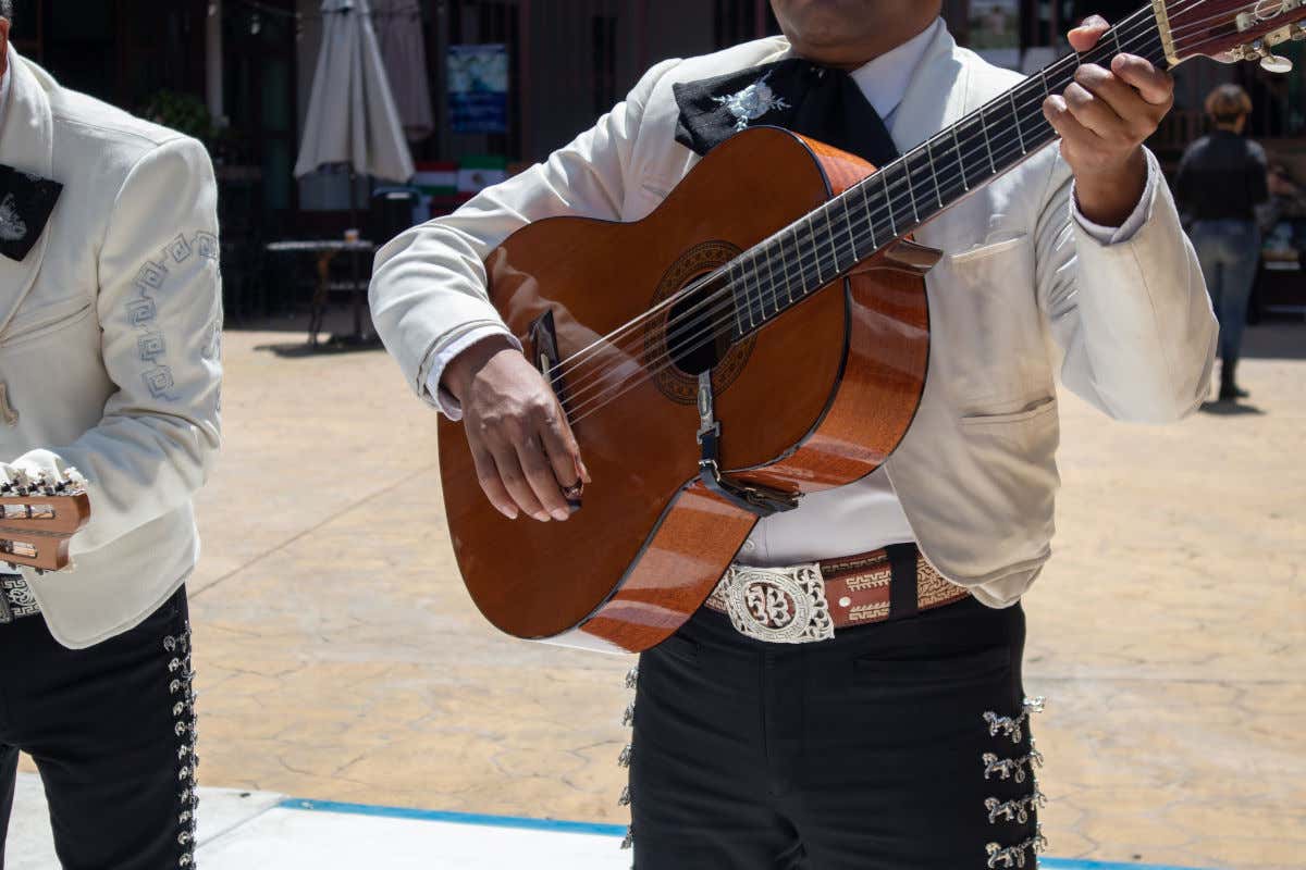 Dos mariachis vestidos con ropa elegante y tocando la guitarra