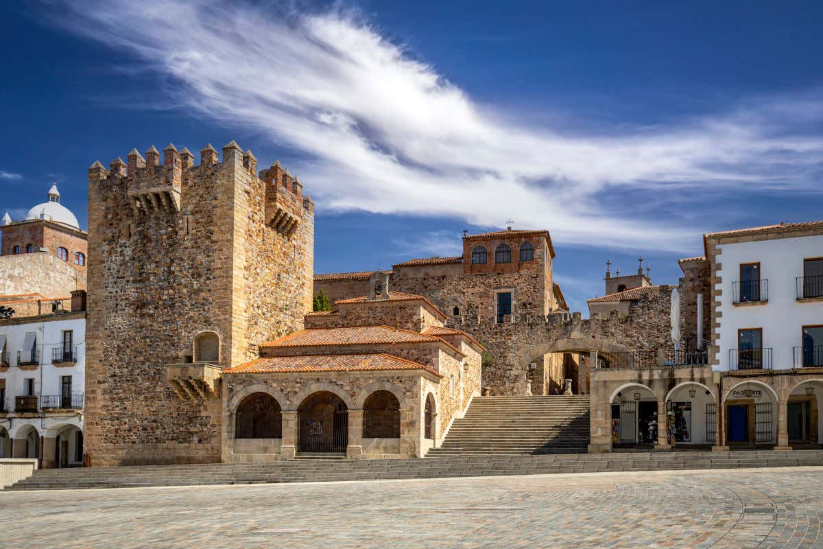 La Plaza Mayor de Cáceres en un día parcialmente nublado y con varios edificios y torreones de piedra en primer plano