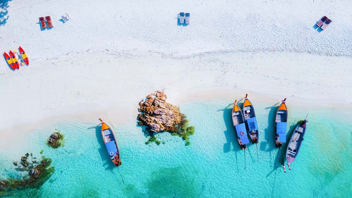 Vista aérea de una playa en Tailandia con varios botes de cola larga, el típico barco tailandés