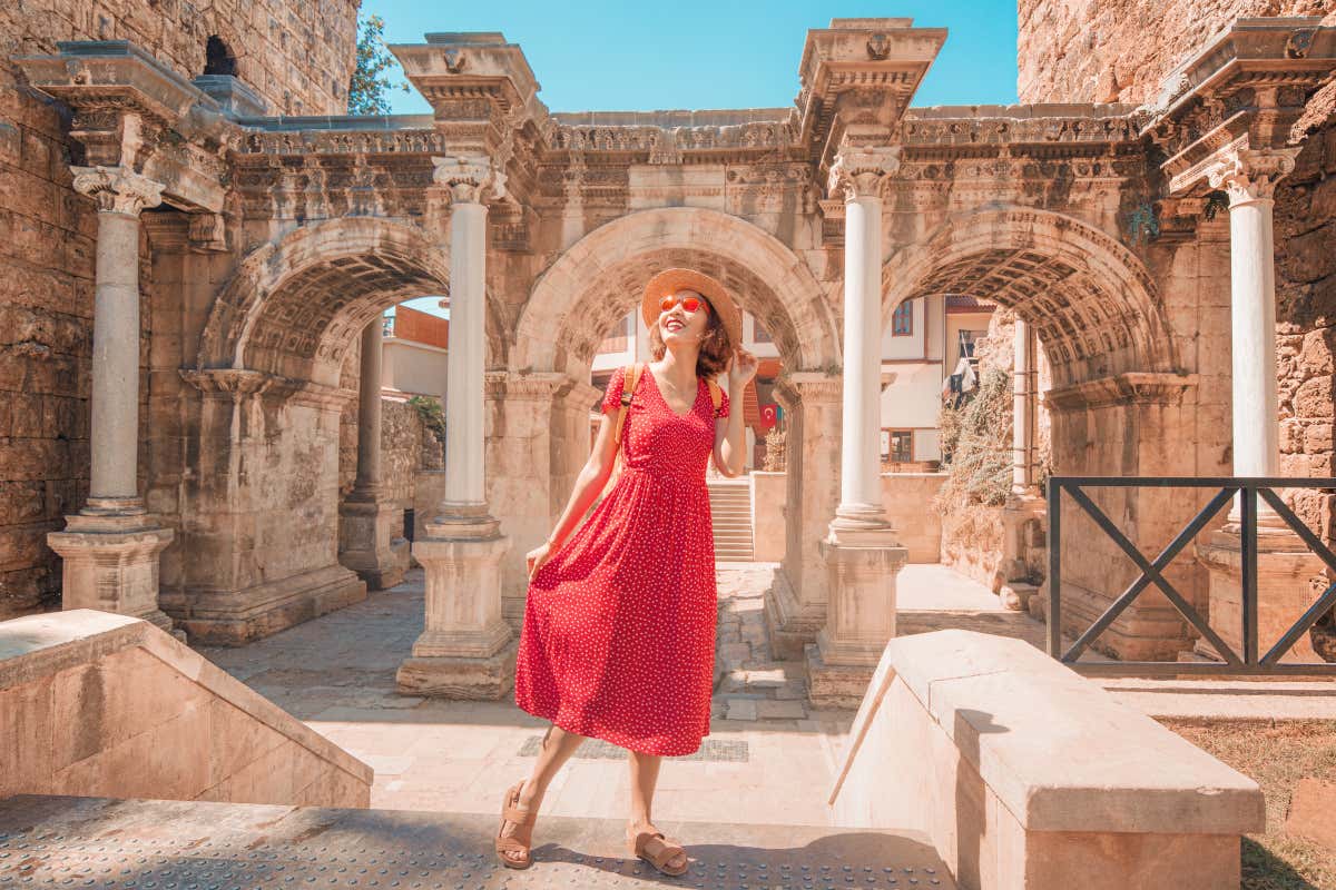 Una mujer con vestido rojo frente al arco de la Puerta de Adriano, el principal acceso a Kaleiçi, el casco viejo de Antalya